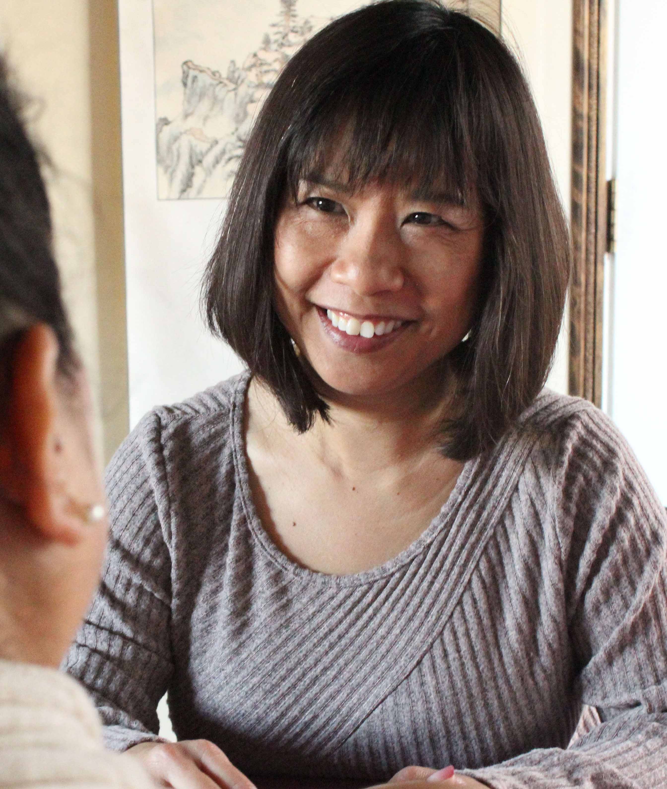 lynn cheng, acupuncturist in Fremont CA, sitting across a table with a patient and discussing her needs
